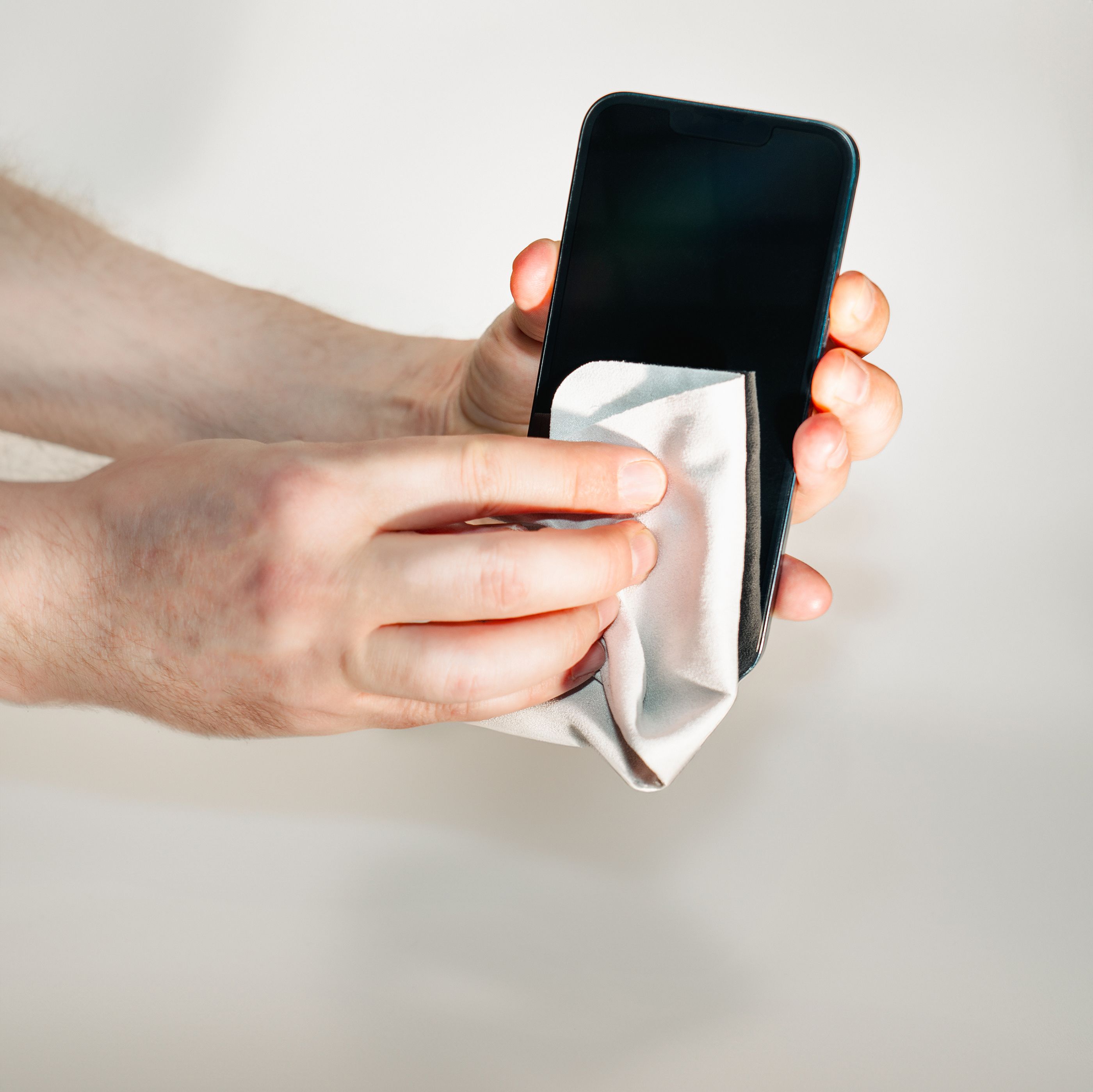 Tangan mengelap skrin telefon dengan kain lembut