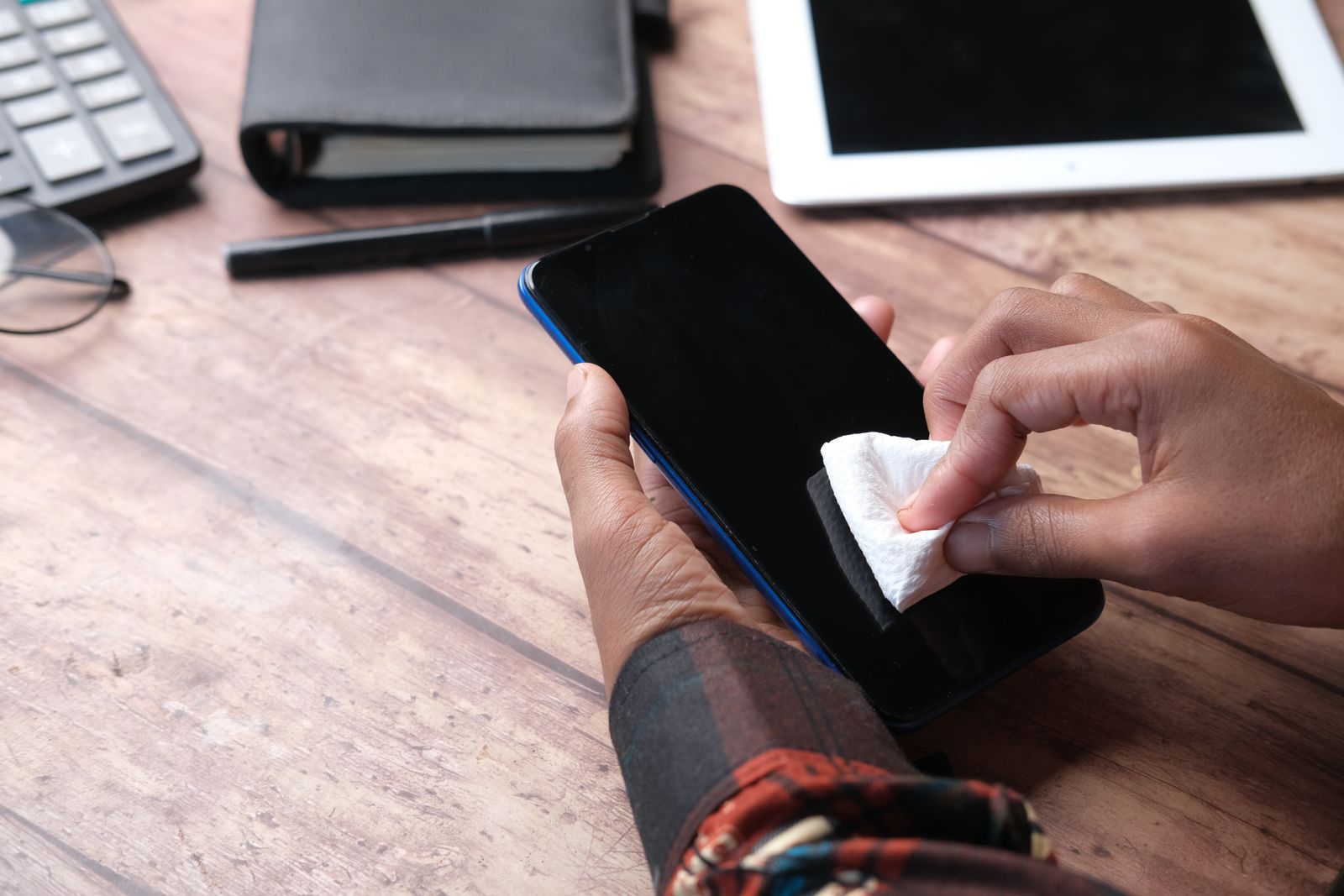 Permukaan telefon dilap dengan kain di meja kerja