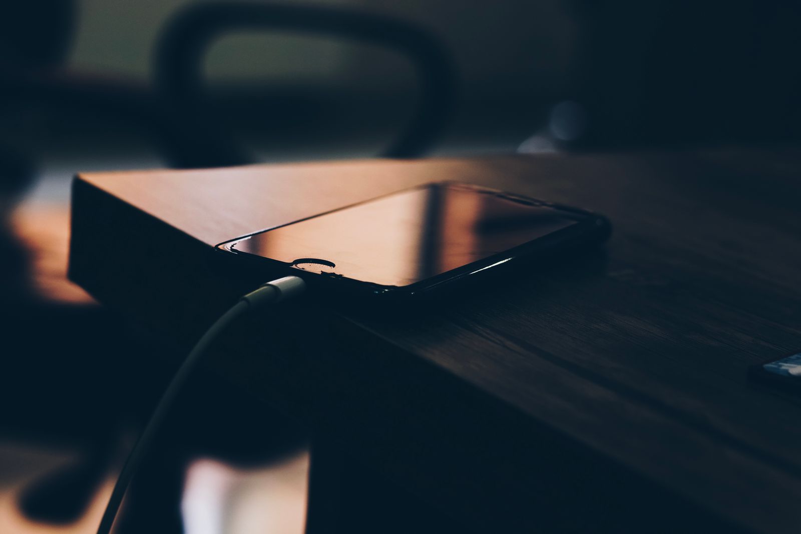 Telefon dan kabel pengecas di atas permukaan kayu