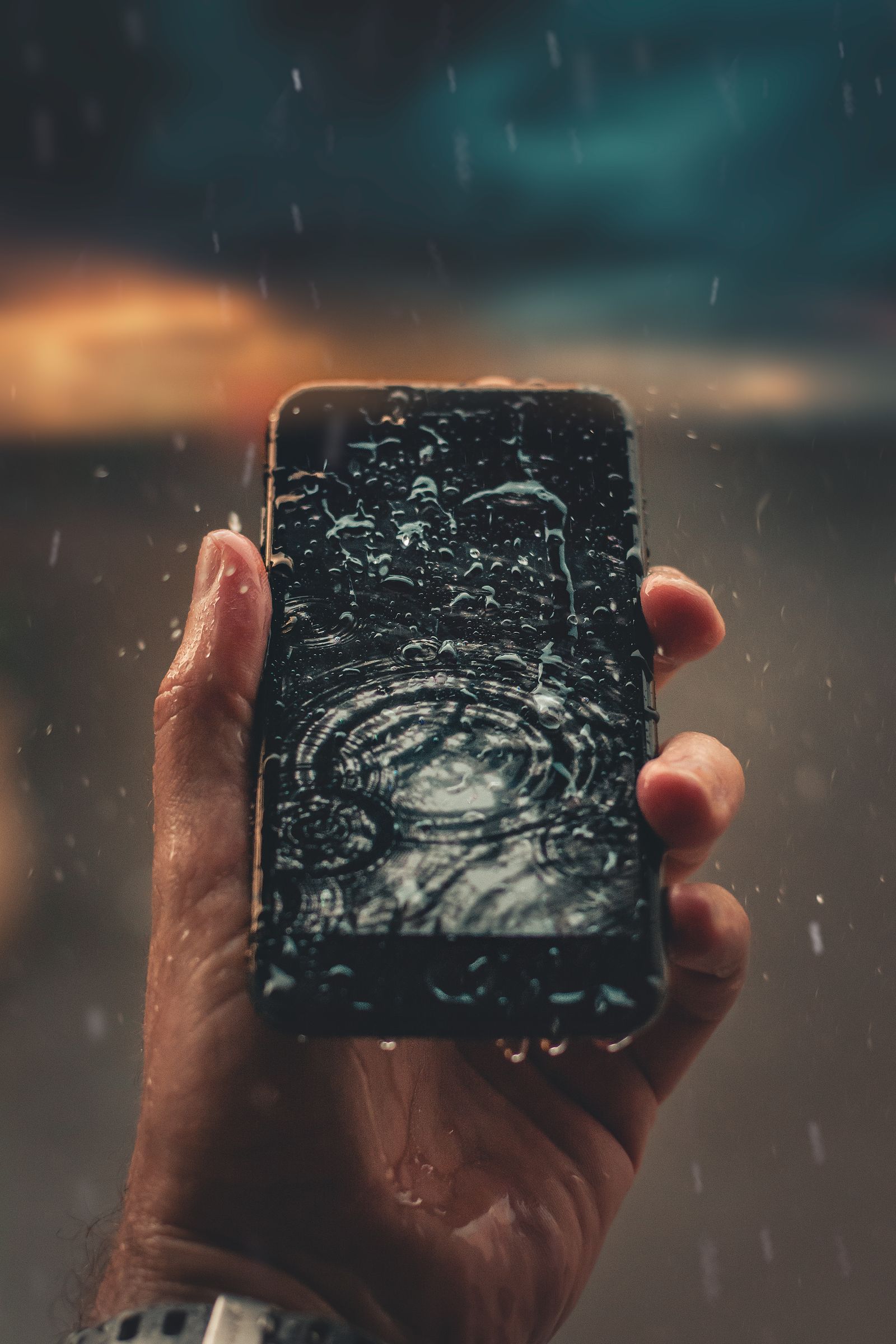 Telefon dengan titisan air dipegang dalam tangan