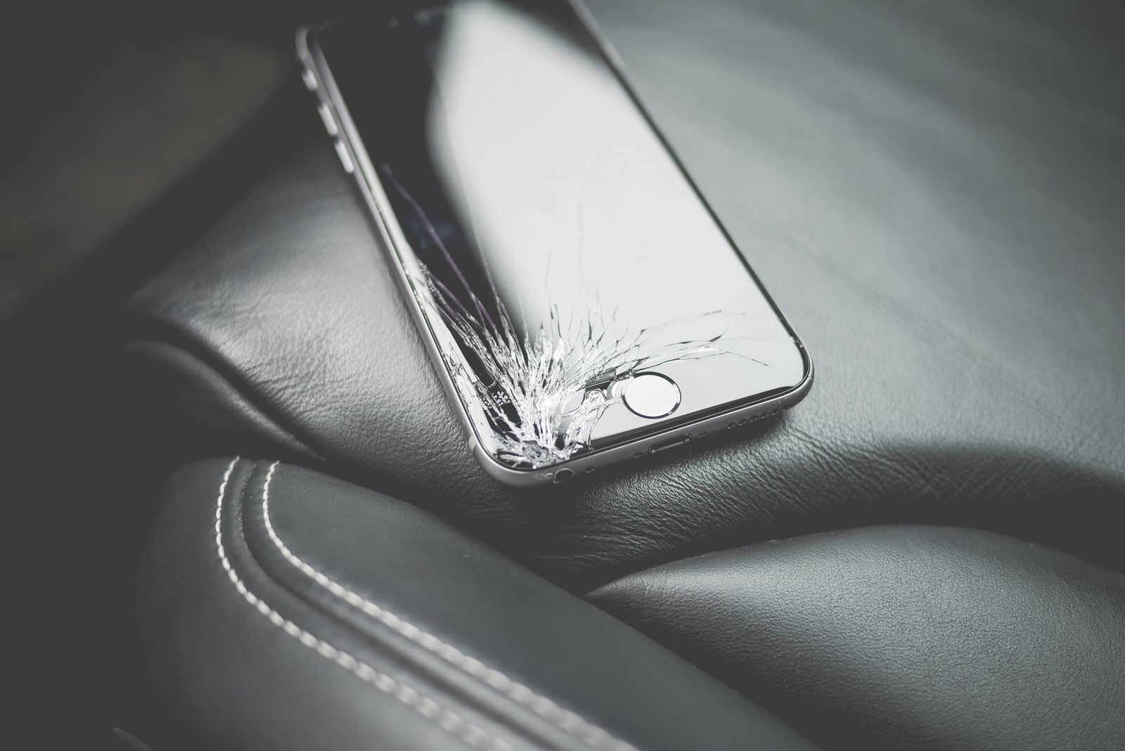 Telefon dengan skrin retak di atas tempat duduk kereta