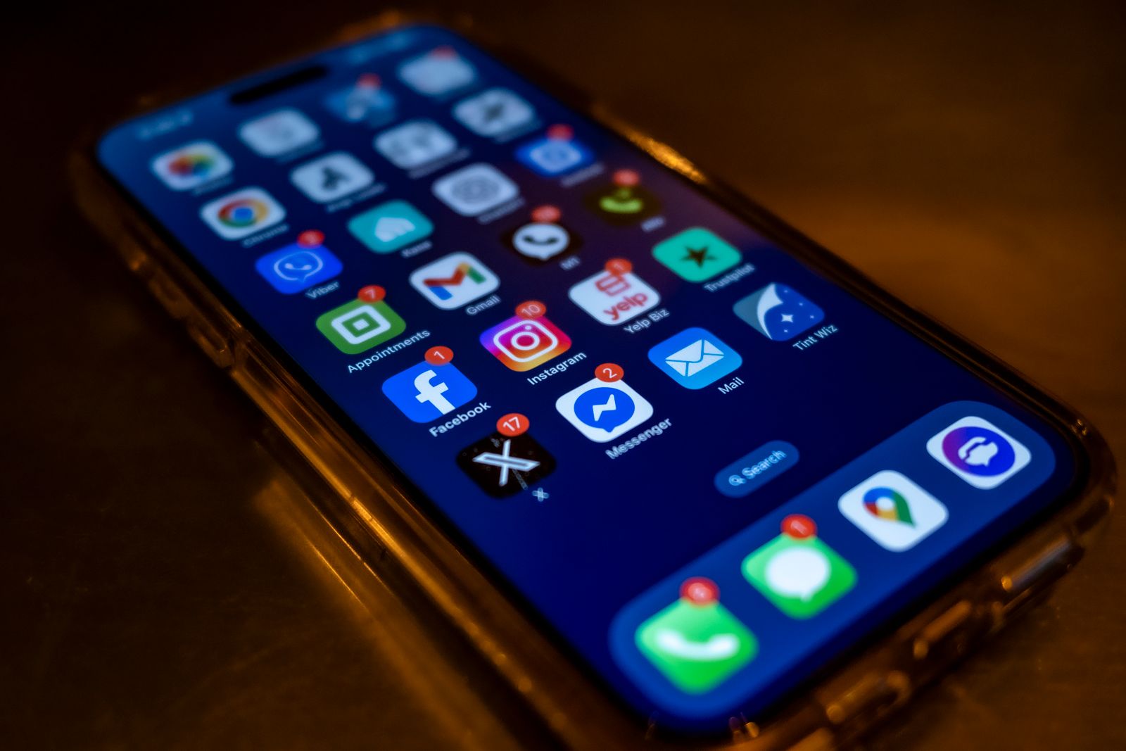 Telefon memaparkan ikon aplikasi di atas permukaan kayu