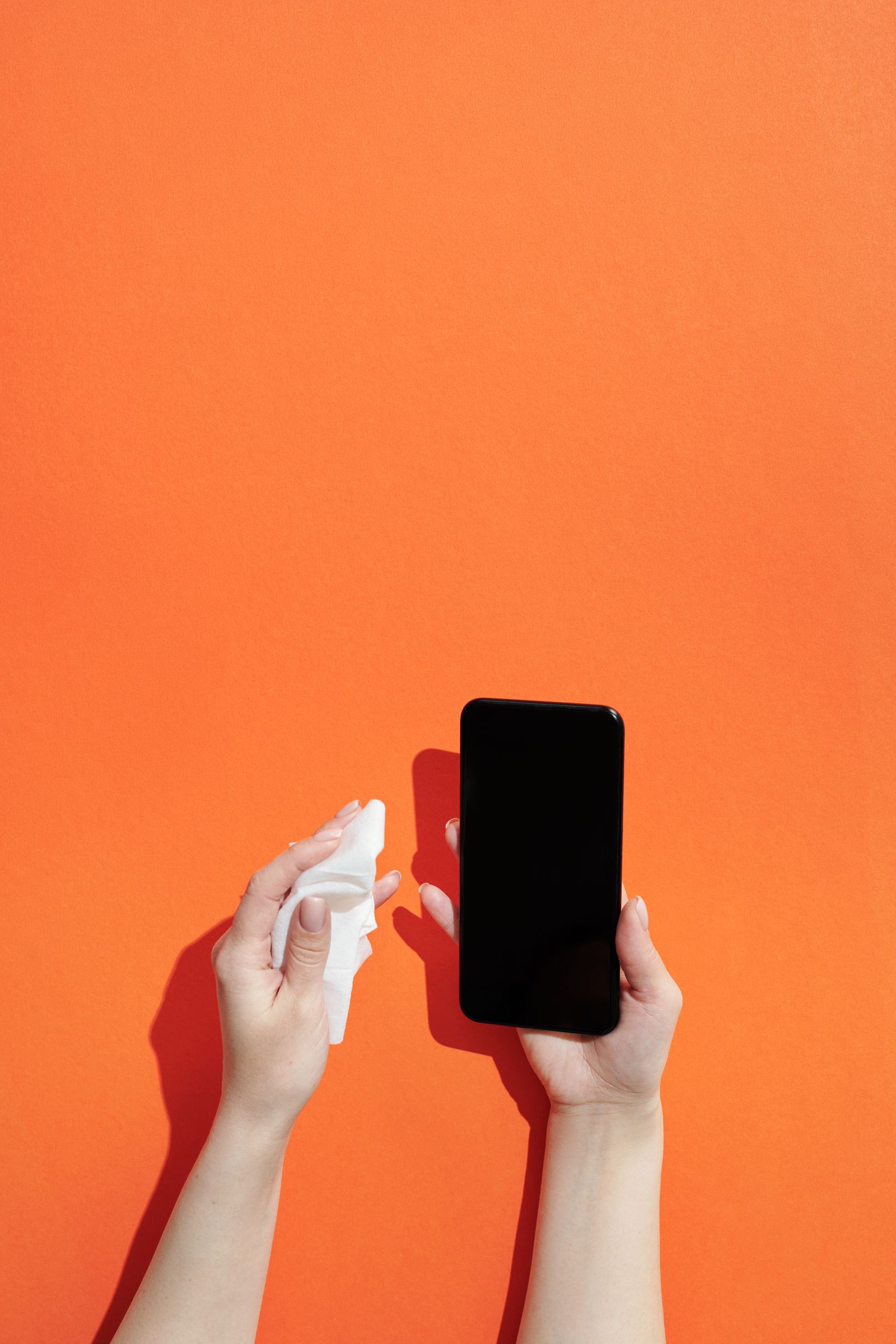 Tangan memegang telefon dan kain pembersihan