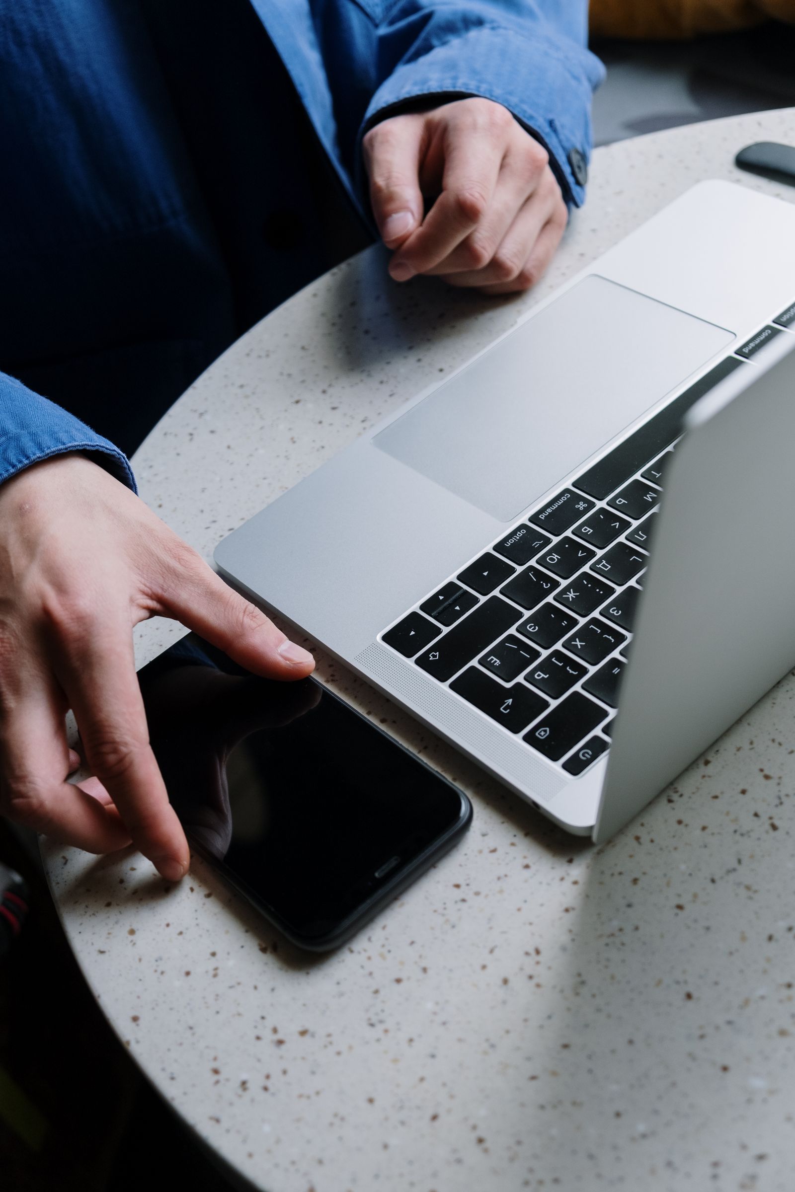 Pengguna menggunakan telefon di meja bersama MacBook