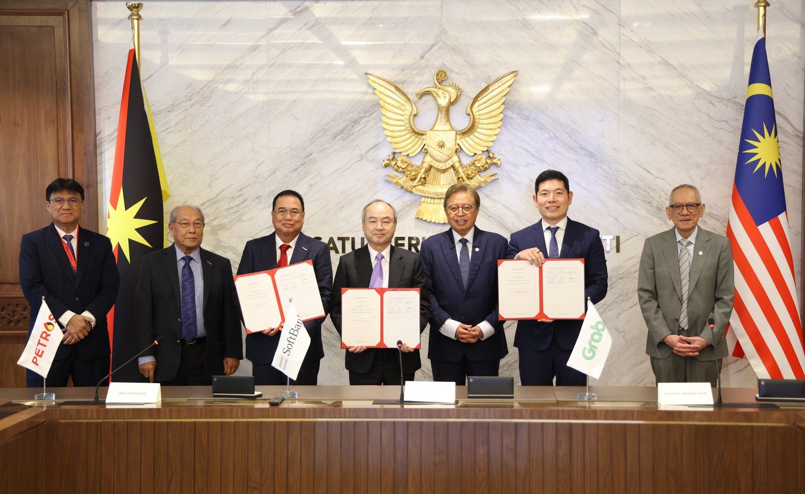 Wakil SoftBank, Grab, PETROS dan Premier Sarawak bergambar sambil memegang dokumen perjanjian.