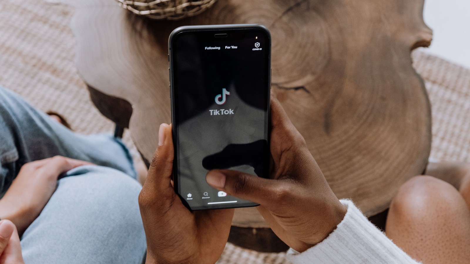 Tangan memegang telefon pintar yang memaparkan aplikasi TikTok.