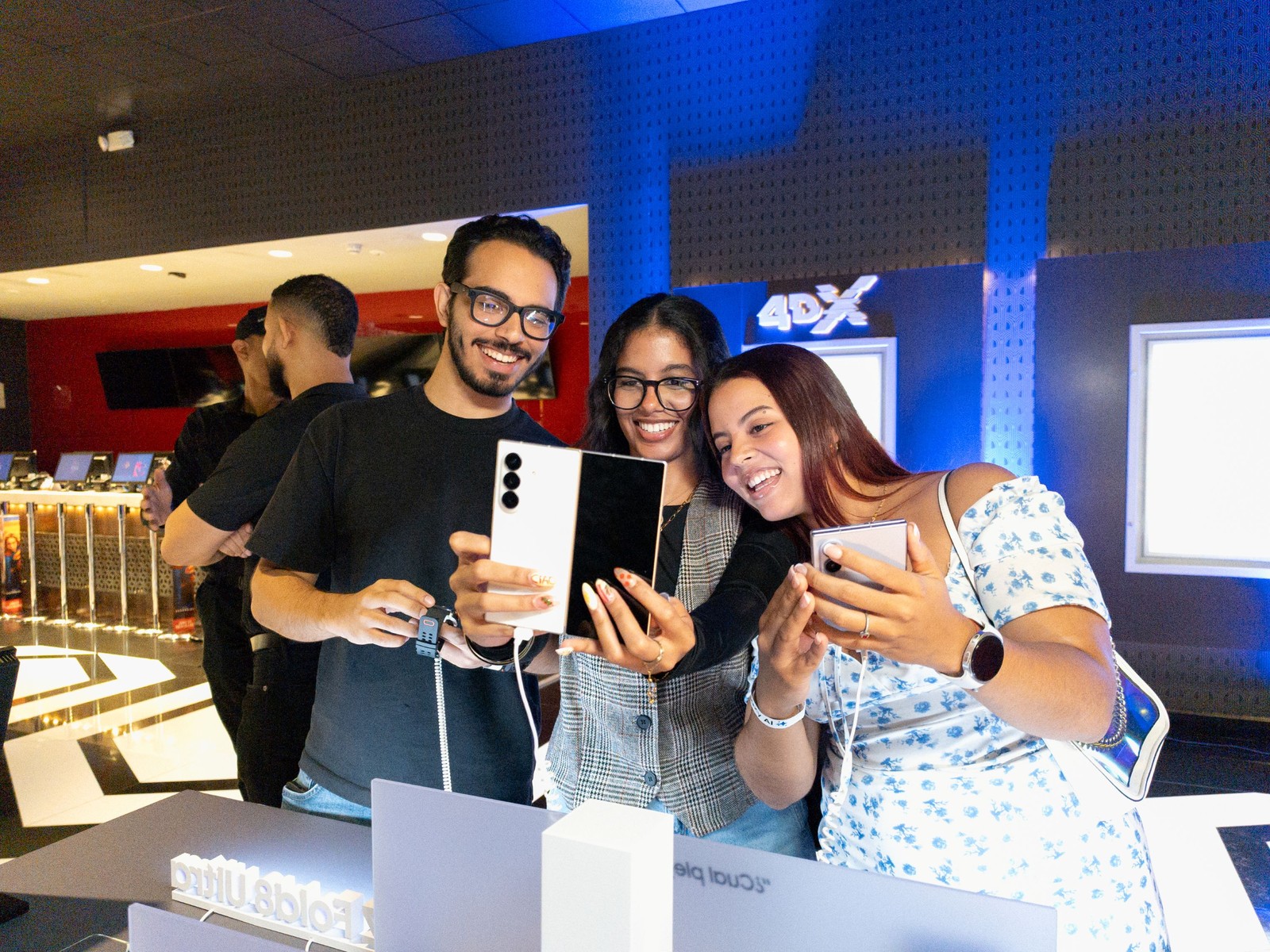 Tiga orang tersenyum melihat telefon lipat Samsung pada unit paparan