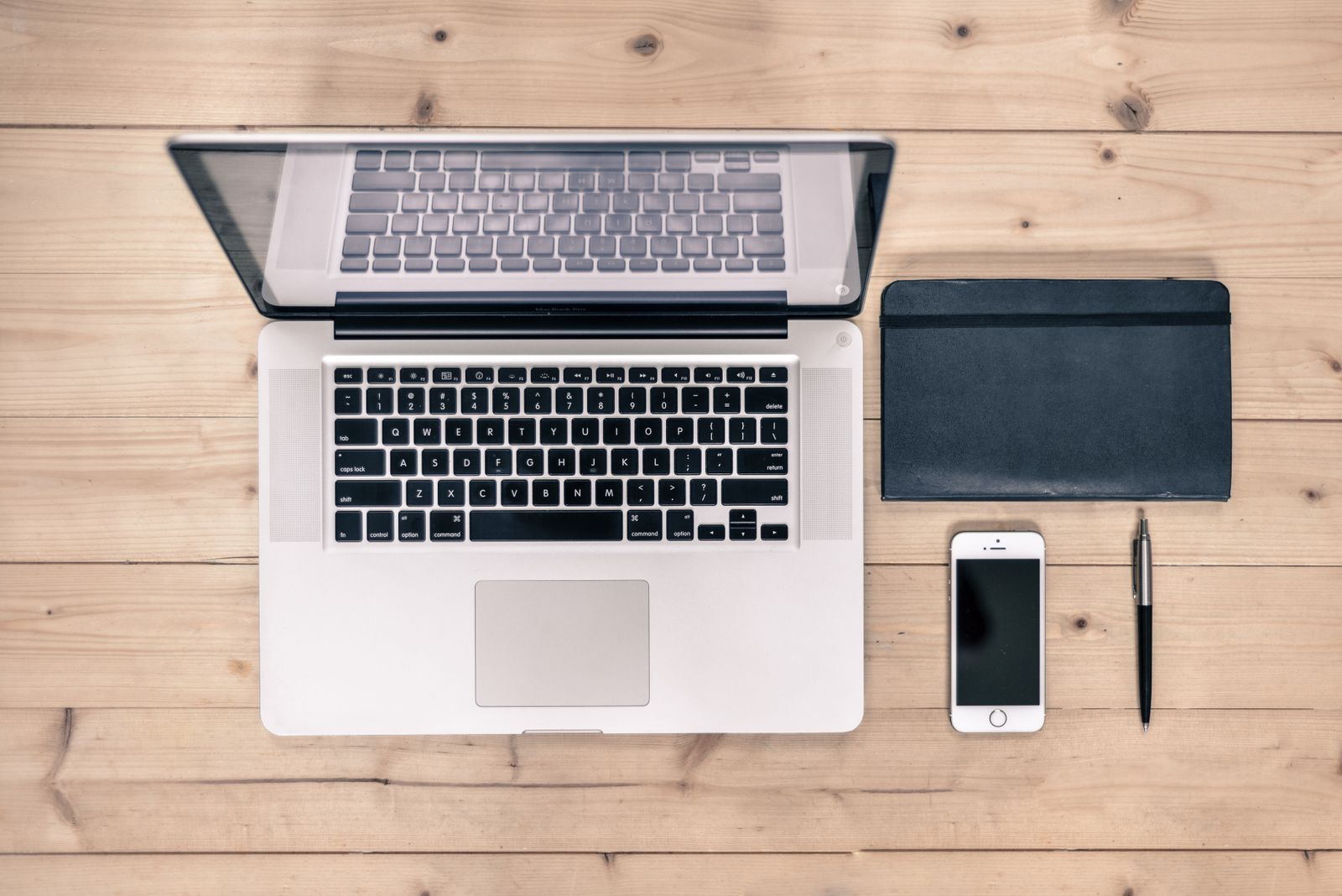 MacBook, telefon dan buku nota di atas meja