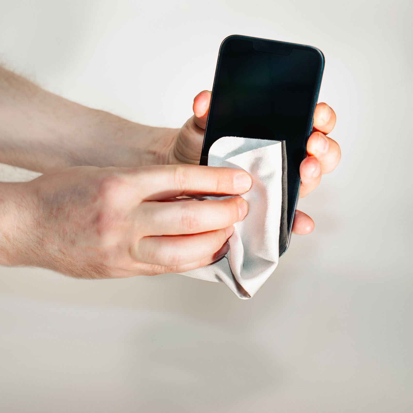 Tangan mengelap permukaan telefon menggunakan kain